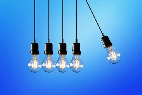 A row of hanging light bulbs with one swinging out